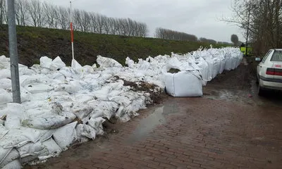 steunberm van zandzakken binnendijks